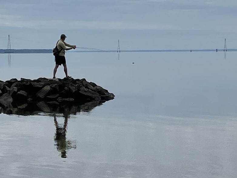 A man standing on top of a rock in the water.