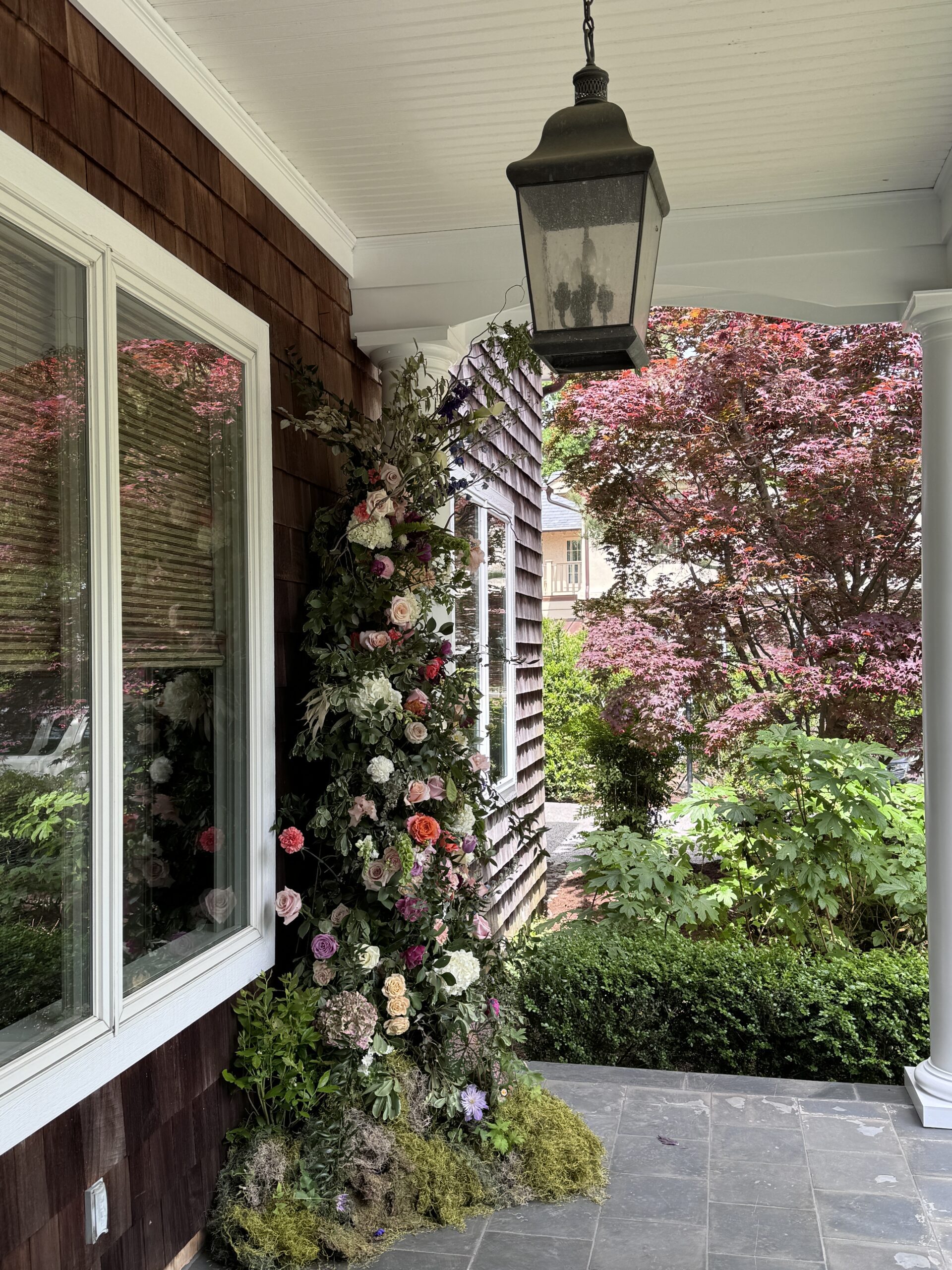 A porch with flowers and trees in the background.