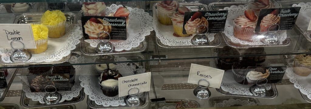 A display case with several different types of cupcakes.